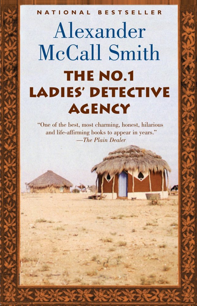 The author and title of book appear above the image of traditional African homes, with thatched roofs. Photograph surrounded by golden and black floral border.