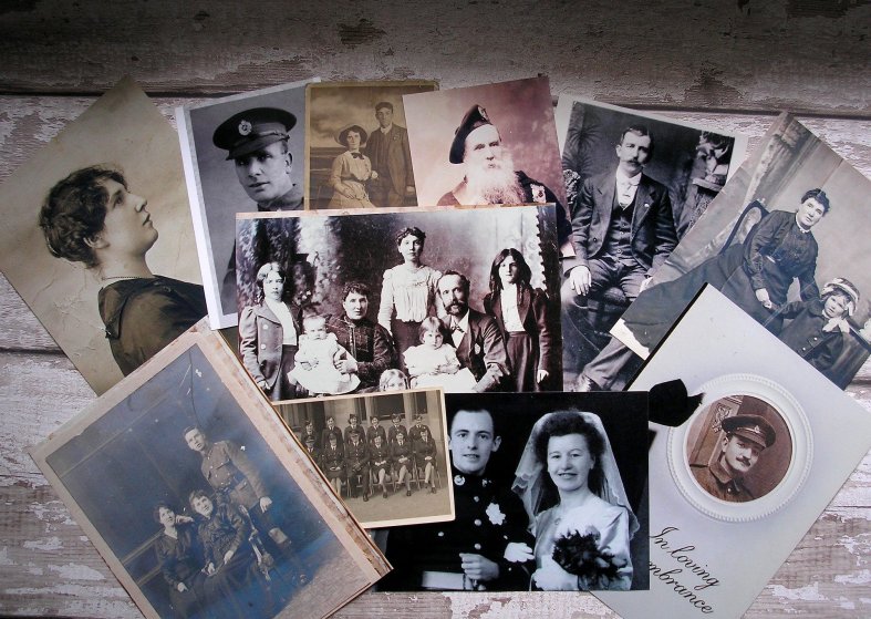 Collage of old photos including military and wedding portraits fanned along wooden table.