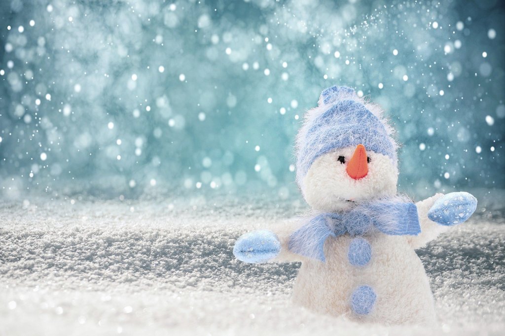 Snowy background with a white felt snowman wearing light blue scarf, mittens,. and hat.