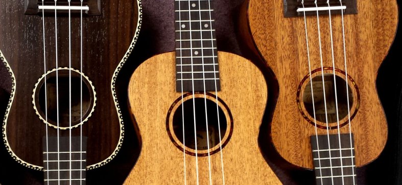 Three ukuleles, set alternating top to bottom, in three finishes - dark, blond, and maple.