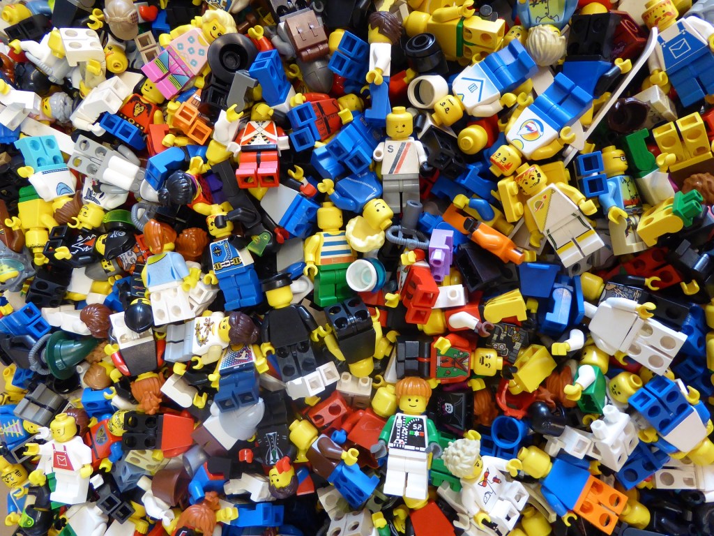 The photograph depicts a jumbled, colorful pile of Lego blocks and figurines.