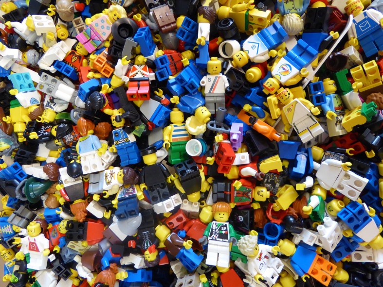 The photograph depicts a jumbled, colorful pile of Lego blocks and figurines.