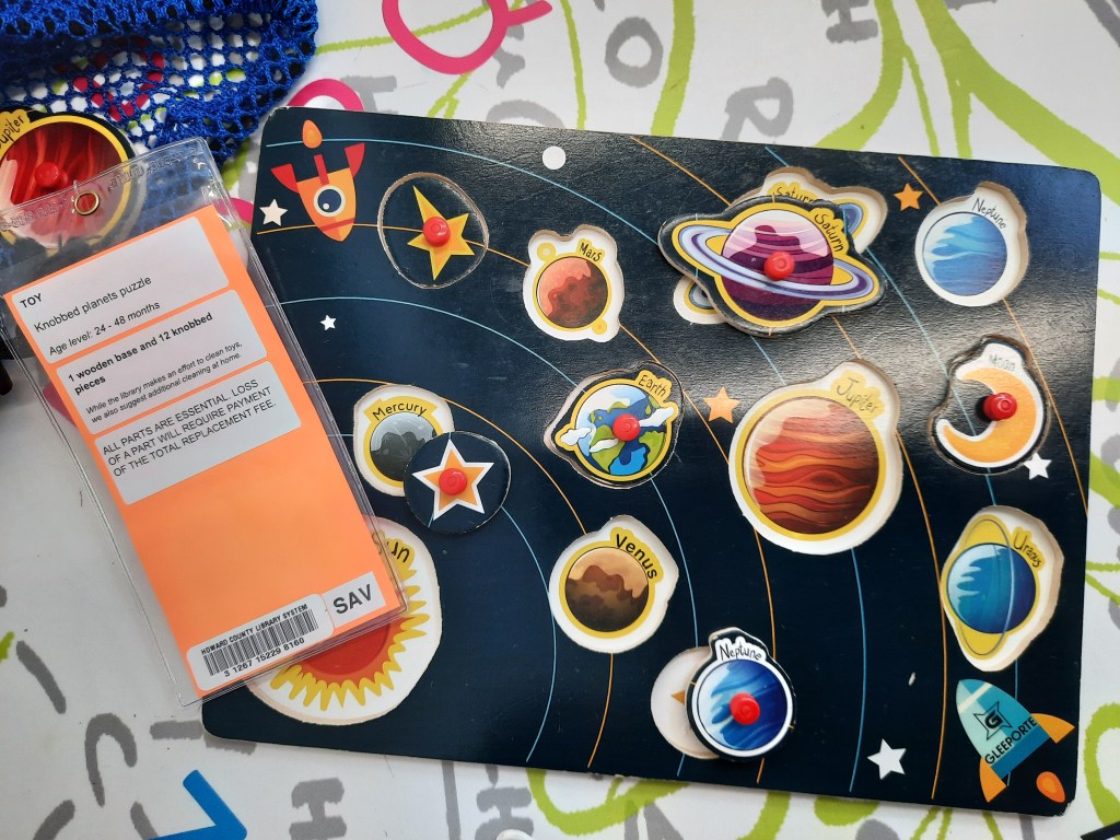 You can see a black puzzle of the solar system that includes brightly colored planets and other objects, as well as the orange toy label.