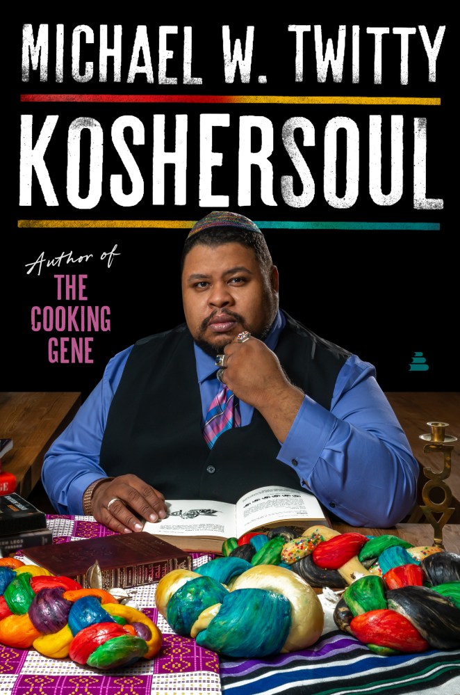 Cover of Michael Twitty's new book shows him in formal vest and tie, sitting at a table covered in braided bread, reading a book.