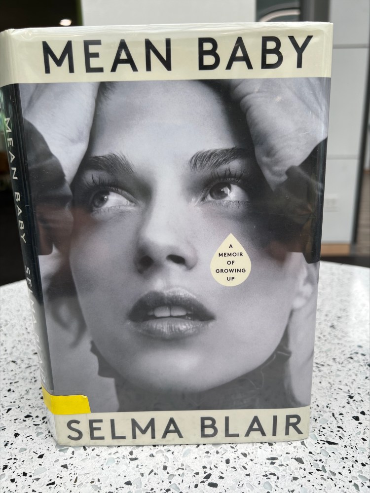 The picture shows the book on a marble-topped table. The cover is a picture of author Selma Blair, her hands on the top of her head, looking skyward.