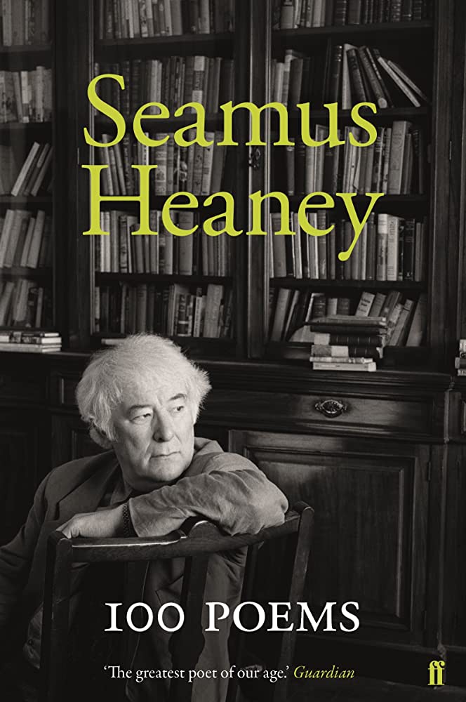 Poet Seamus Heaney sitting in front of full bookshelves, looking over the back o