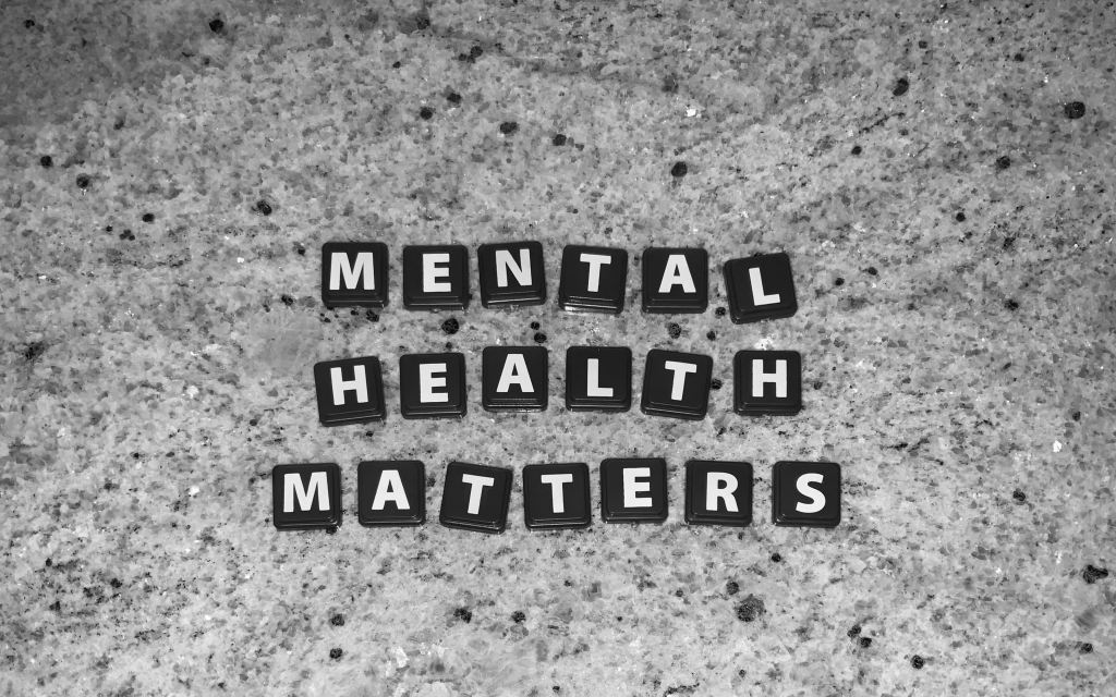 The photograph shows lettered tiles in black and white spelling out the words "Mental Health Matters" against the background of a black and silver quartz countertop.