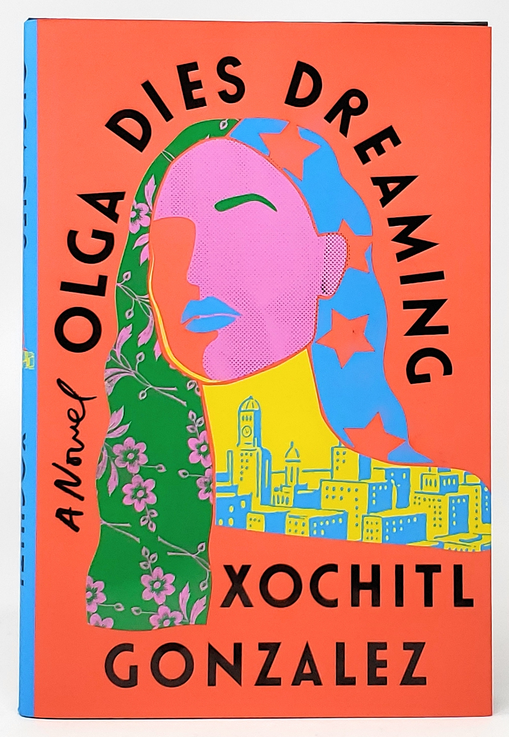 A bright red cover features a color-block illustration of a woman's face in pink, with patterns of stars and flowers in her hair, all resting above a yellow and blue cityscape.