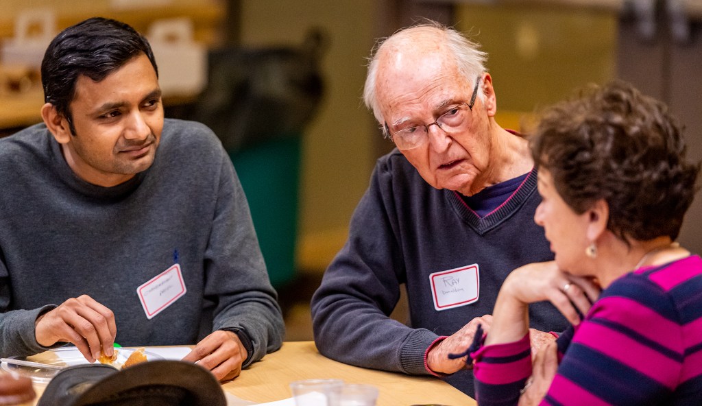 Three people in conversation around a table.