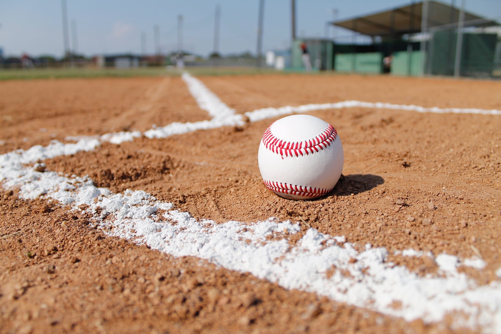 A baseball sits inside the chalk lines of a batter's box, with red seam showing prominently.
