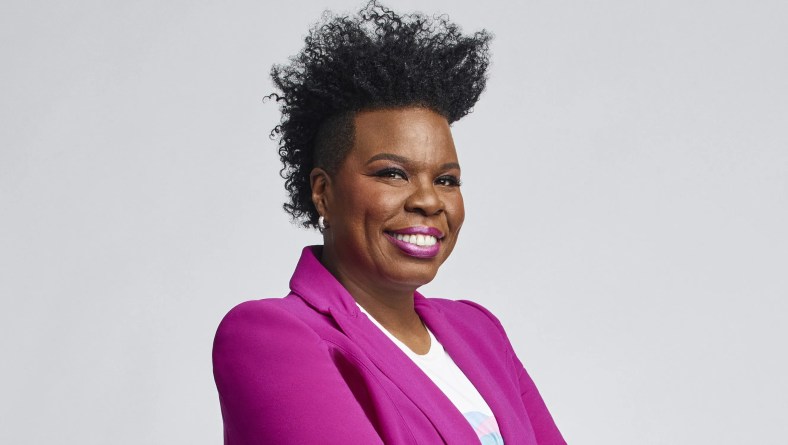 Leslie Jones with her hair teased up, dressed in a bright pink jacket with a white Tshirt.
