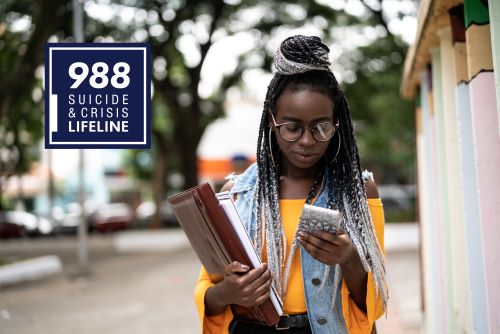 PSA ad: a young Black woman wearing glasses looks down at her cell phone while her other arm is full of books. A blue square to the left says: 988 Suicide and Crisis Lifeline