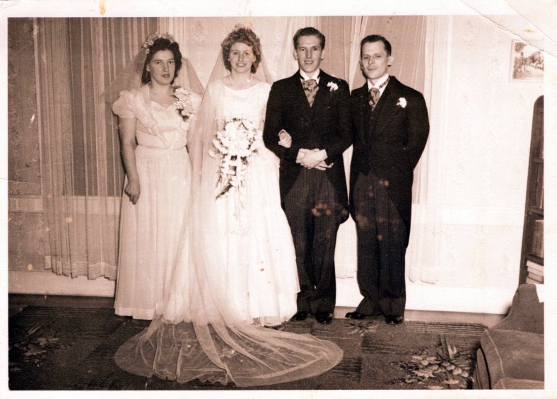 Black and white photo of a bridal party standing in front of a window.