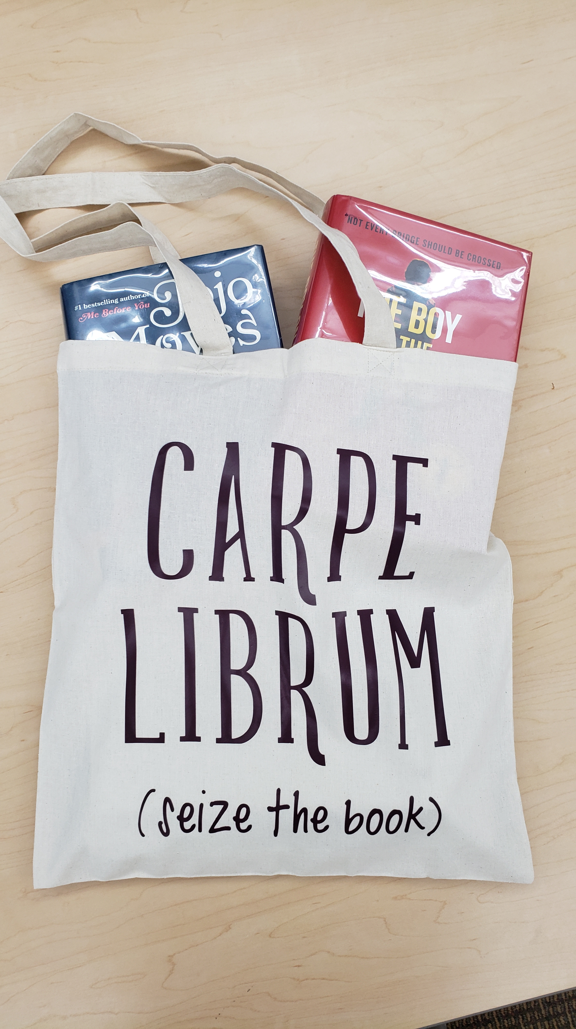 An off-white canvas bag that says Carpe Librum (seize the book) with two books