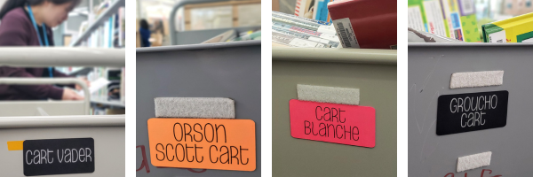 The short end of four book carts with punny names: Cart Vader, Orson Scott Cart, Cart Blanche, and Groucho Cart.