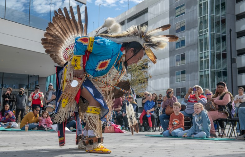 A man in full Native American regalia performs a traditional dance in downtown Columbia.