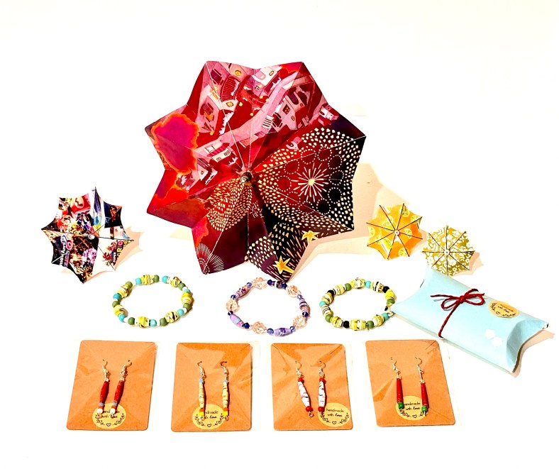The image shows papercrafted mini-parasols in shades of red and yellow, above three bracelets, one gift-wrapped package, and four cards which each have a set of drop earrings attached to them.