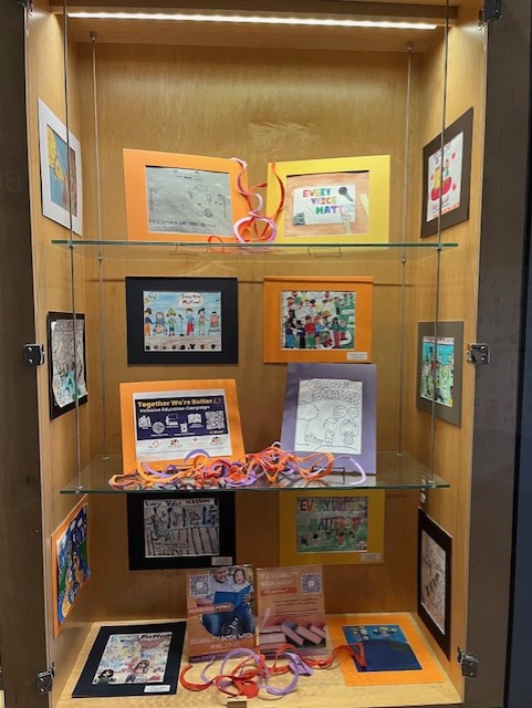 The photograph depicts a selection of the student artwork from the "Every Voice Matters" student exhibit in the Miller Branch display cases.