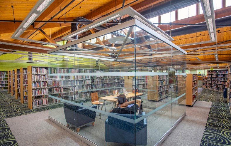 A photo of a glass box at HCLS Central Branch, upstairs with a view of the open, wooden ceiling.