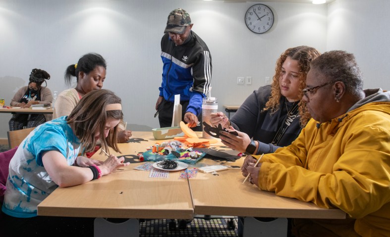 Several people sit around an arts and crafts station working on projects.