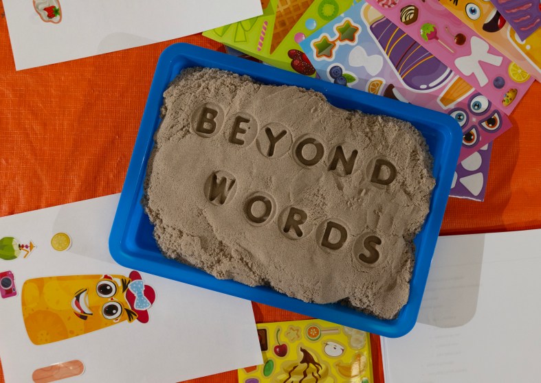 Letters spelling "BEYOND WORDS" are pressed into clay, with other crafts on the table beneath.