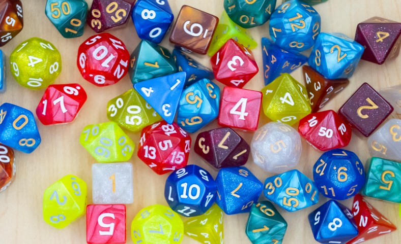 A collection of brightly colored dice of all different sizes.